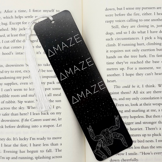 Black Sci-Fi Amaze Alien Metal Bookmark with white tassel and celestial star design on an open book