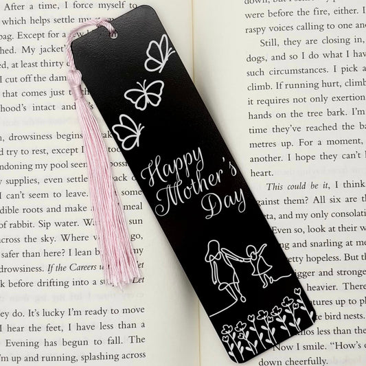 A black Happy Mothers Day Metal Bookmark on an open book with a pink tassel