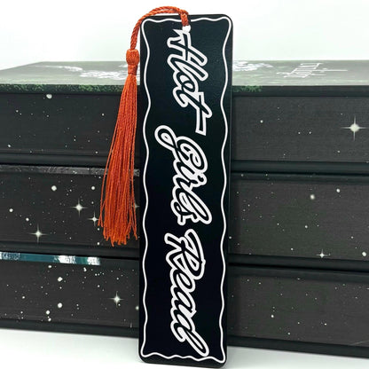 Hot Girls Read Metal Engraved Bookmark with a red tassel on a patterned background.