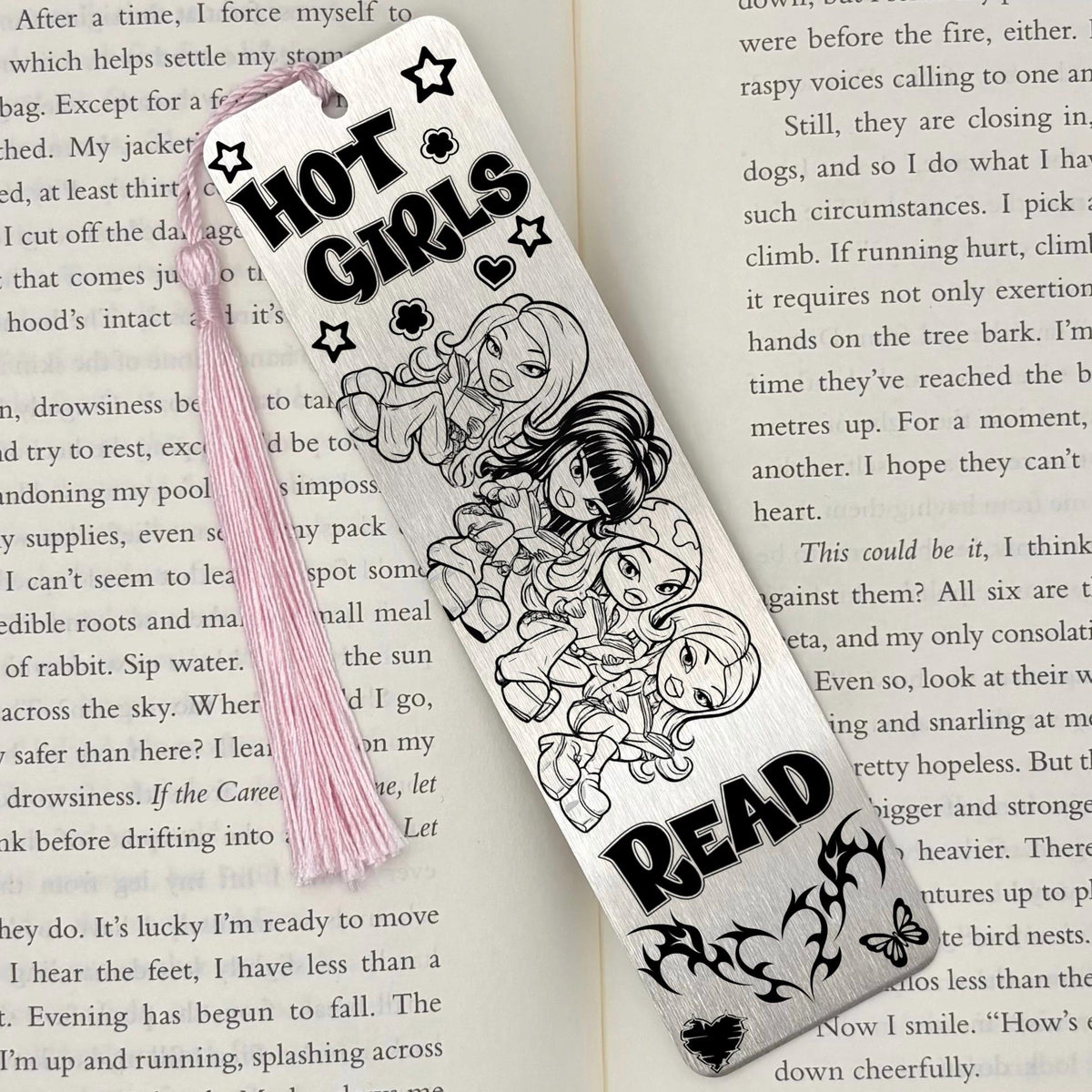 A brushed silver Y2K Hot Girls Read Metal Bookmark on an open book with a pink tassel