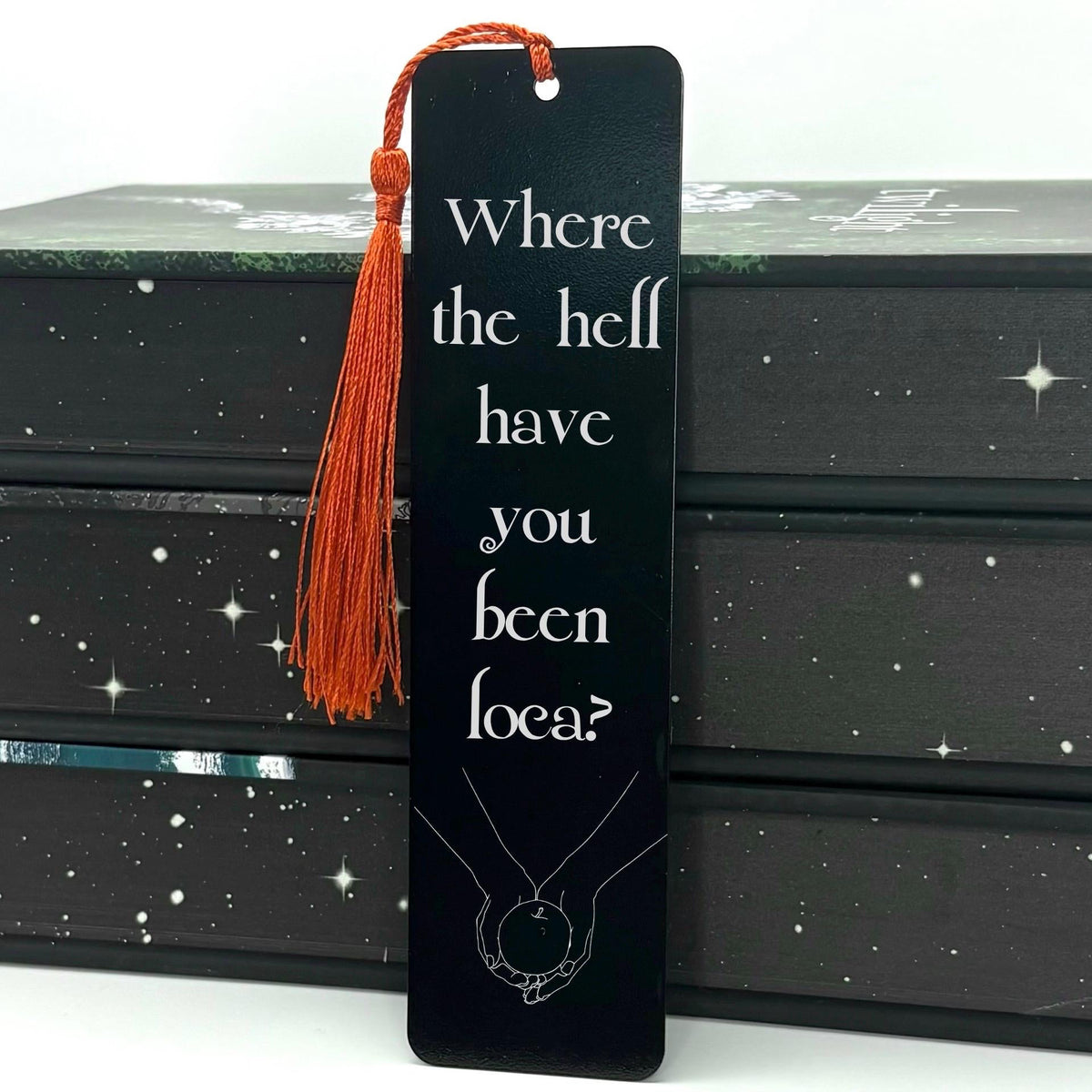     Where Have You Been Loca Metal Bookmark in black with white quote design, hand illustration and red tassel.