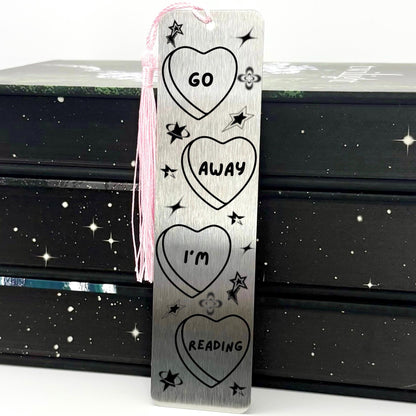     Go Away I’m Reading Metal Bookmark in brushed silver with heart and celestial design and pink tassel