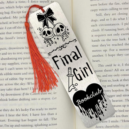     Brushed silver Final Girl Slasher Genre Metal Bookmark with red tassel displayed on an open book.