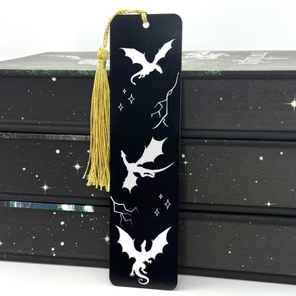 Black Fantasy Dragons Metal Bookmark with gold tassel standing against stack of books