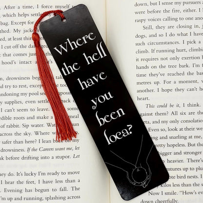     Where Have You Been Loca Metal Bookmark in black with red tassel, displayed on an open book.