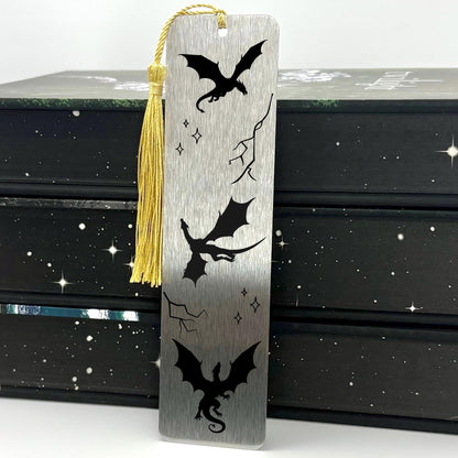 Brushed silver Fantasy Dragons Metal Bookmark with gold tassel standing against stack of books
