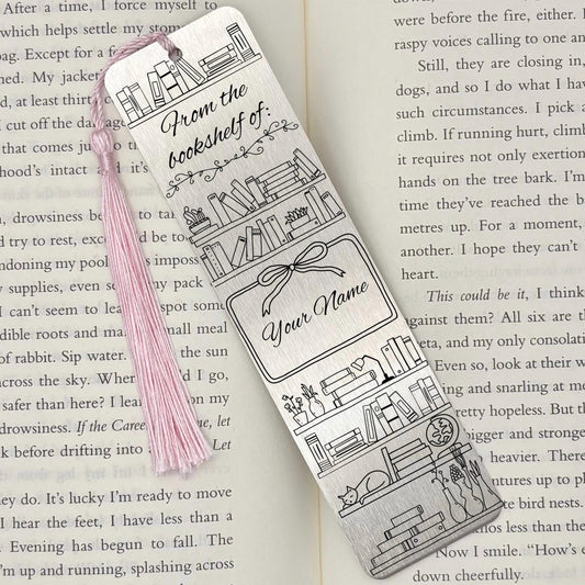 A brushed silver Personalised Name Bookshelf Metal Bookmark on an open book with a pink tassel