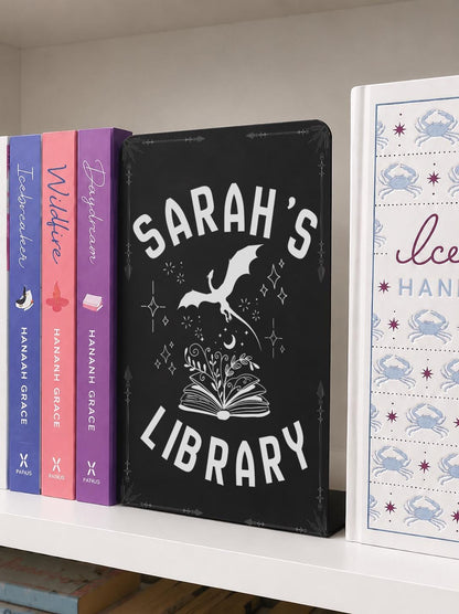     Custom Name Dragon Library Metal Bookshelf Sign displayed between books on a bookshelf