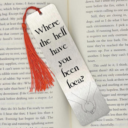     Where Have You Been Loca Metal Bookmark in brushed silver with black lettering and red tassel, displayed on an open book.