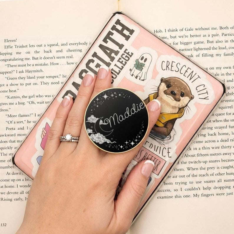     Personalised Name Celestial Metal Kindle Grip personalised with Maddie, shown in use on a decorated e-reader
