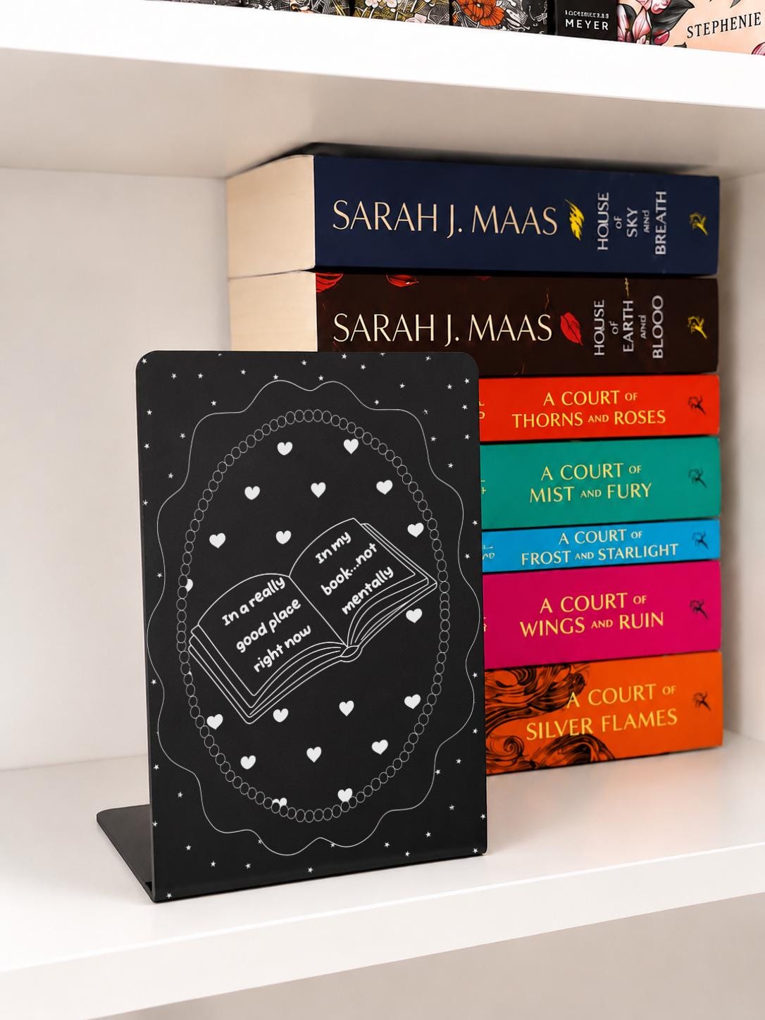     In A Good Place In My Book Metal Bookshelf Bookends in black with open book, hearts and stars design displayed with fantasy books