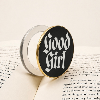     Good Girl Metal MagSafe Kindle Grip with black and silver gothic design displayed on an open book