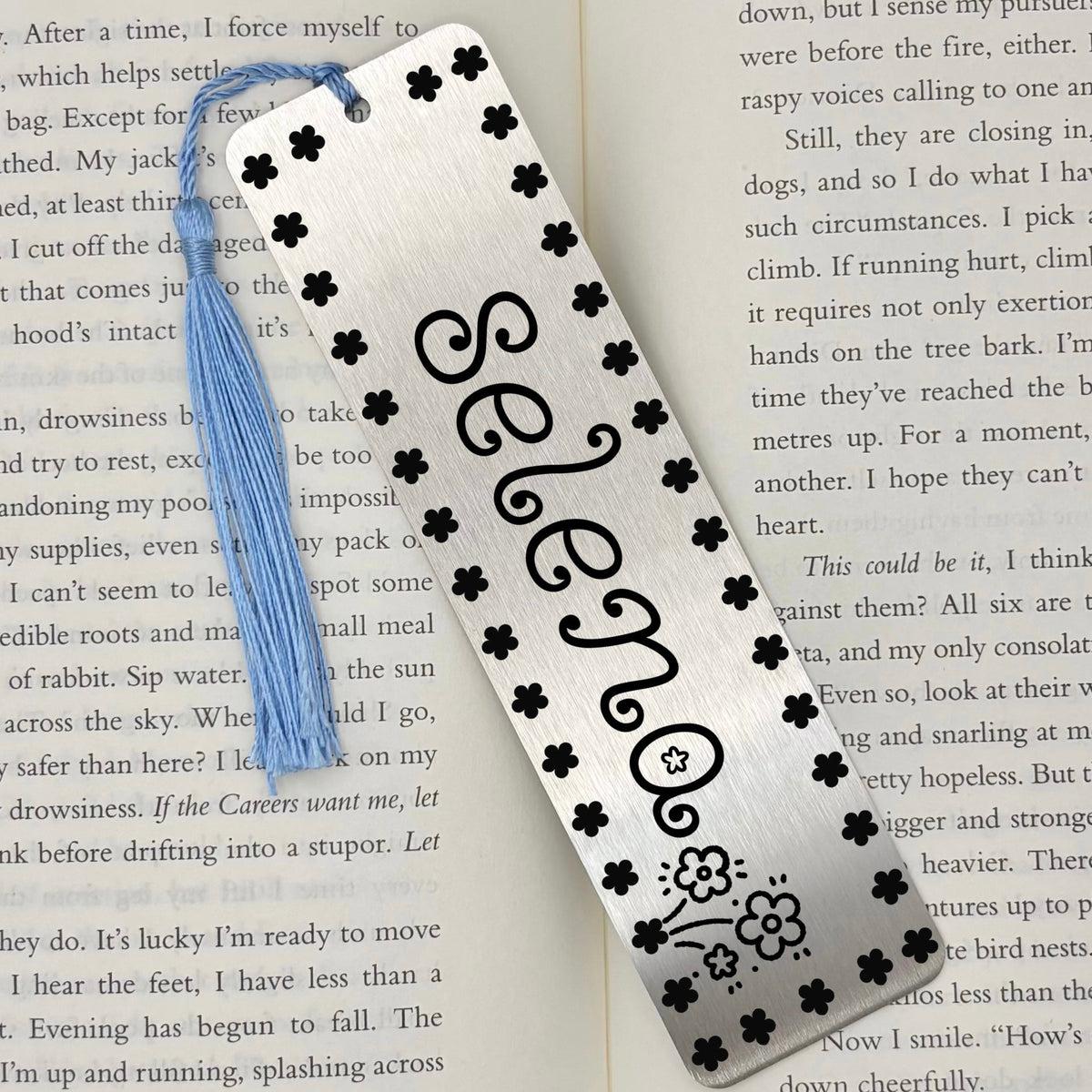 Brushed silver Personalised Name Floral Metal Bookmark on an open book with light blue tassel