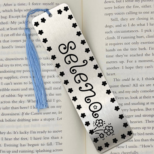 Brushed silver Personalised Name Floral Metal Bookmark on an open book with light blue tassel