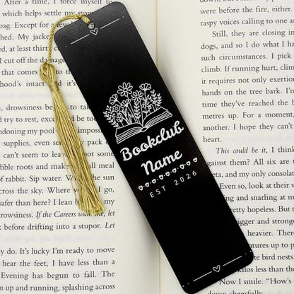 A black Personalised Book Club Name Metal Bookmark on an open book with a gold tassel