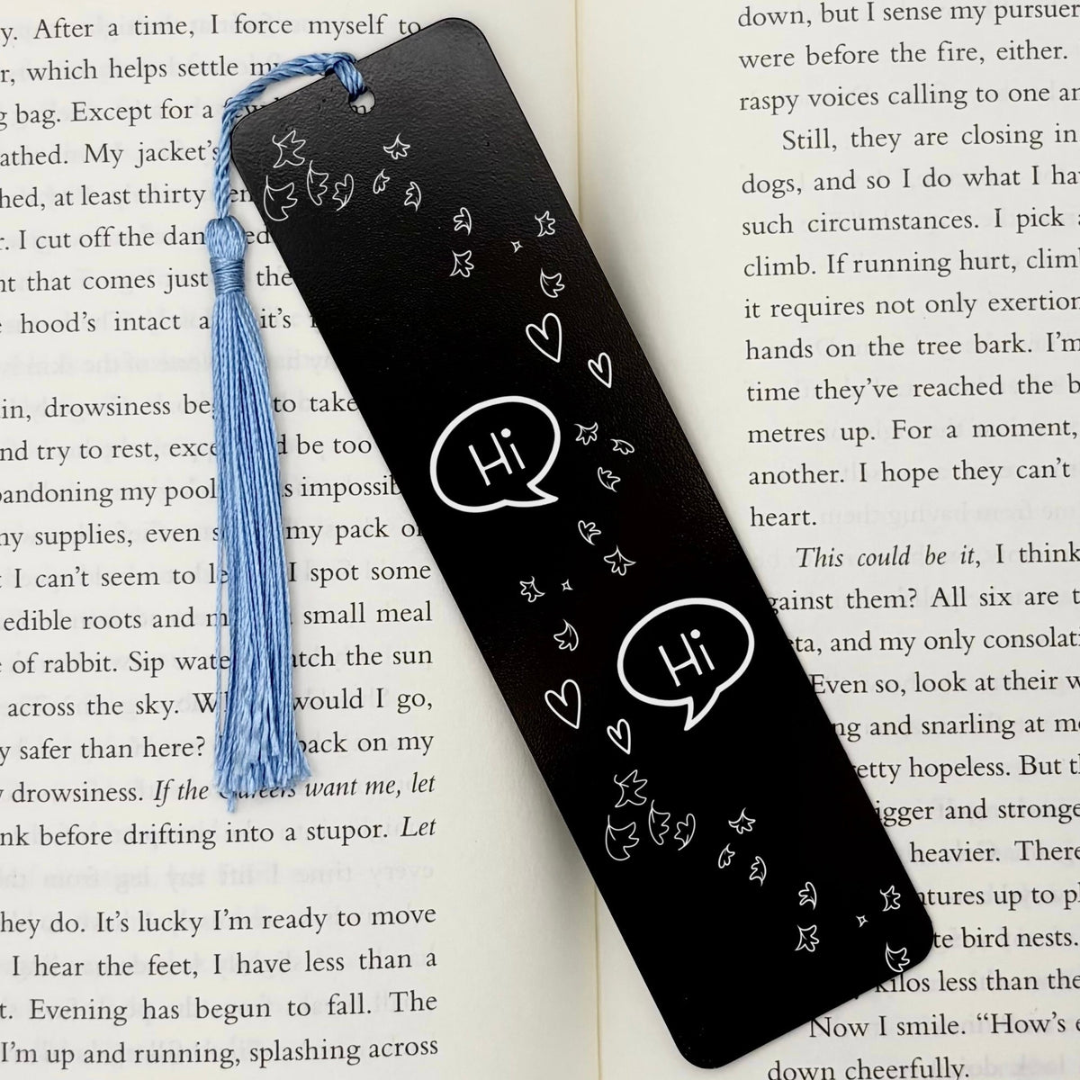     Black Bookish Gay Romance Metal Bookmark displayed inside an open book with blue tassel
