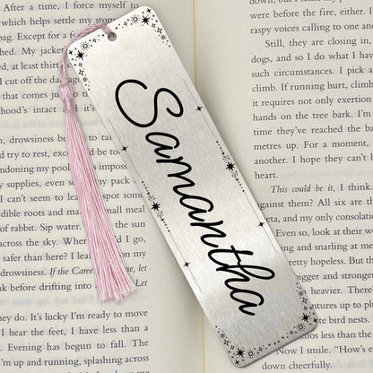 A brushed silver Personalised Name Metal Bookmark on an open book with a pink tassel