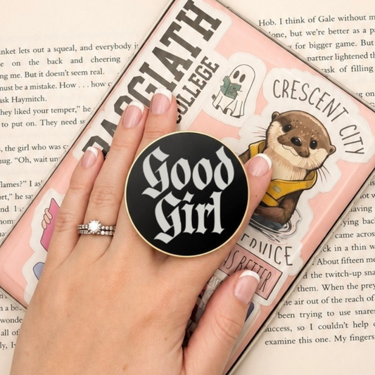     Good Girl Metal MagSafe Kindle Grip attached to a Kindle and held while reading a book