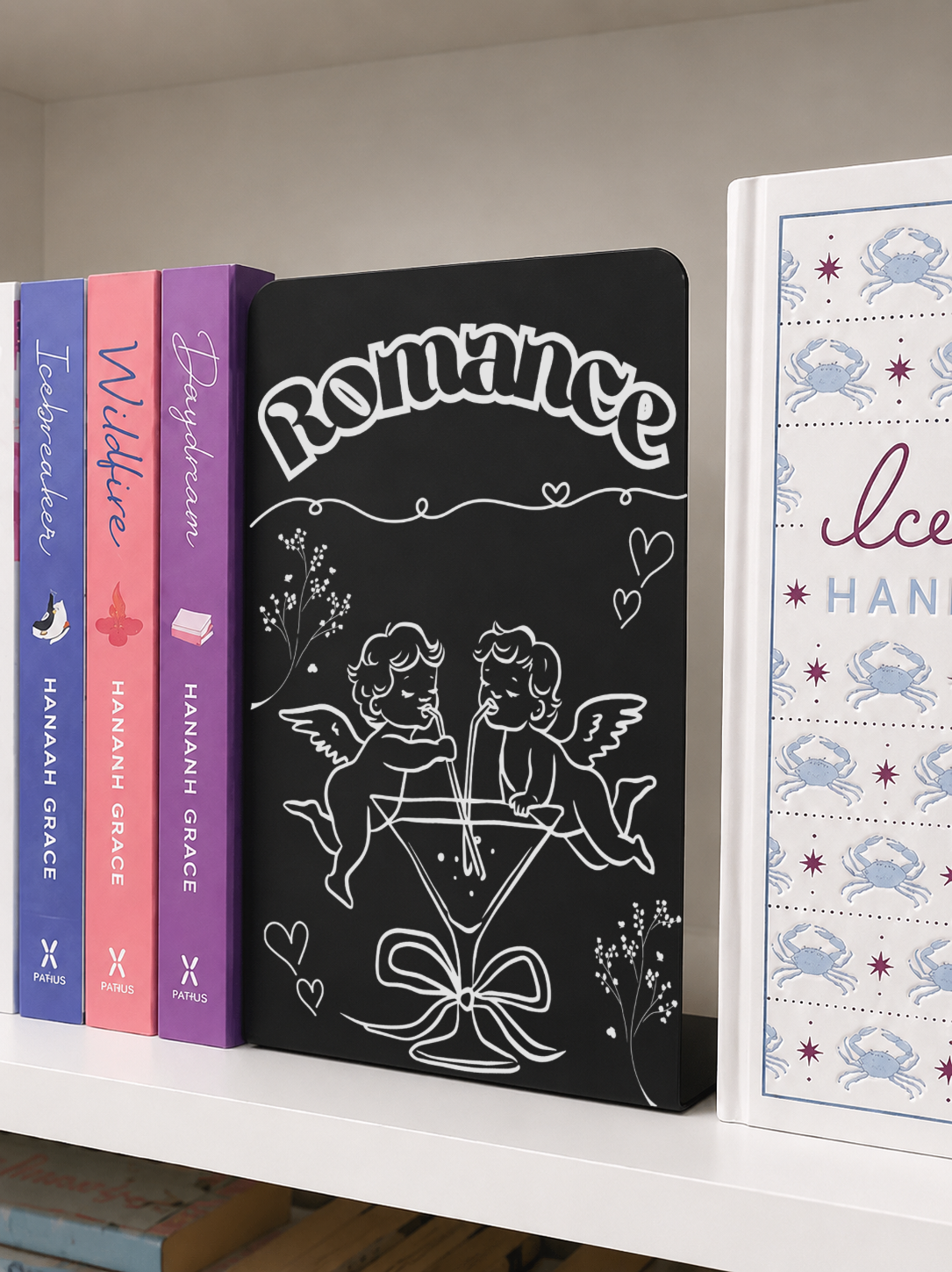     Romance Genre Metal Bookshelf Sign Bookend with engraved cupid and cocktail design on a white bookshelf