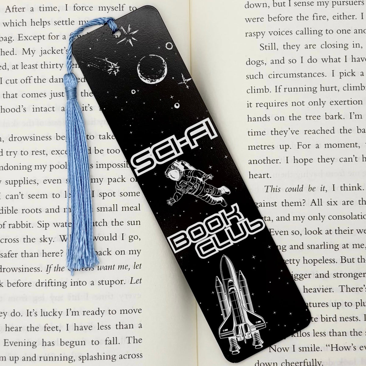     Sci-Fi Book Club Metal Bookmark in black displayed on an open book, featuring astronaut and space-themed engraving.