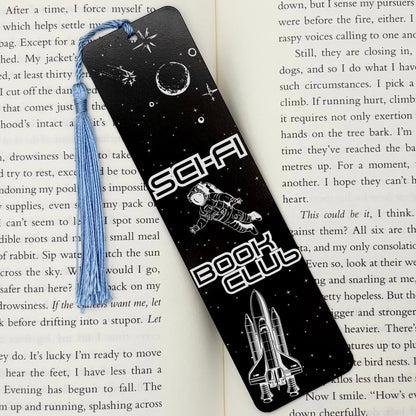     Sci-Fi Book Club Metal Bookmark in black displayed on an open book, featuring astronaut and space-themed engraving.