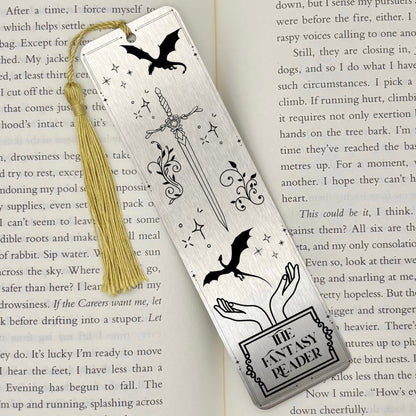 A brushed silver The Fantasy Reader Metal Bookmark on and open book with a gold tassel