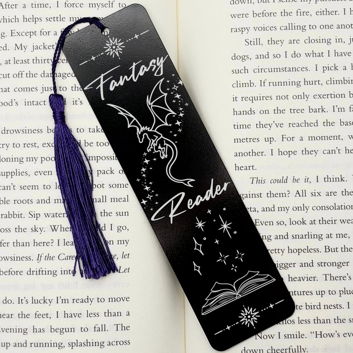 A black Fantasy Reader Dragon Metal Bookmark on and open book with a purple tassel