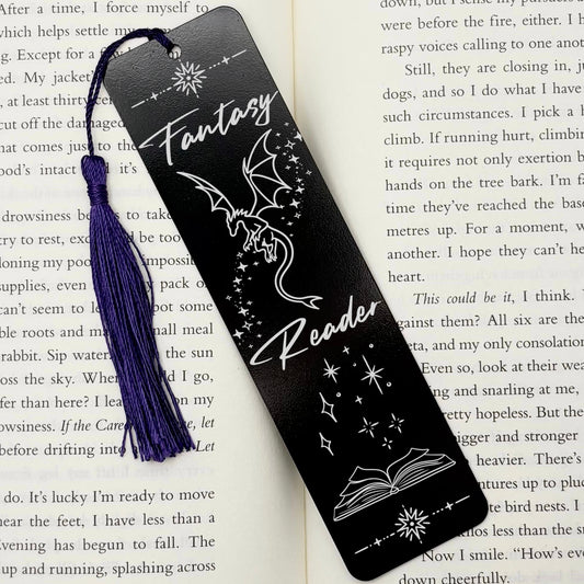 A black Fantasy Reader Dragon Metal Bookmark on and open book with a purple tassel