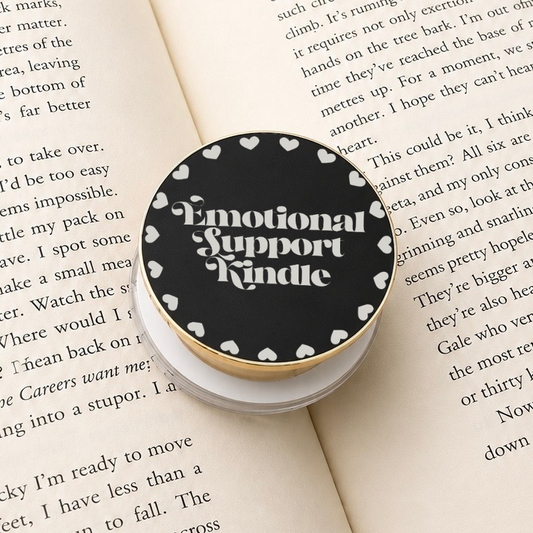 Emotional Support Kindle Metal E-Reader Grip on an open book with heart designs.