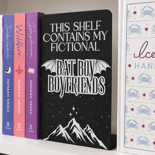 Bat Boys Metal Bookshelf Sign Bookend with engraved fictional bat boy boyfriends design displayed upright between books on a white bookshelf.