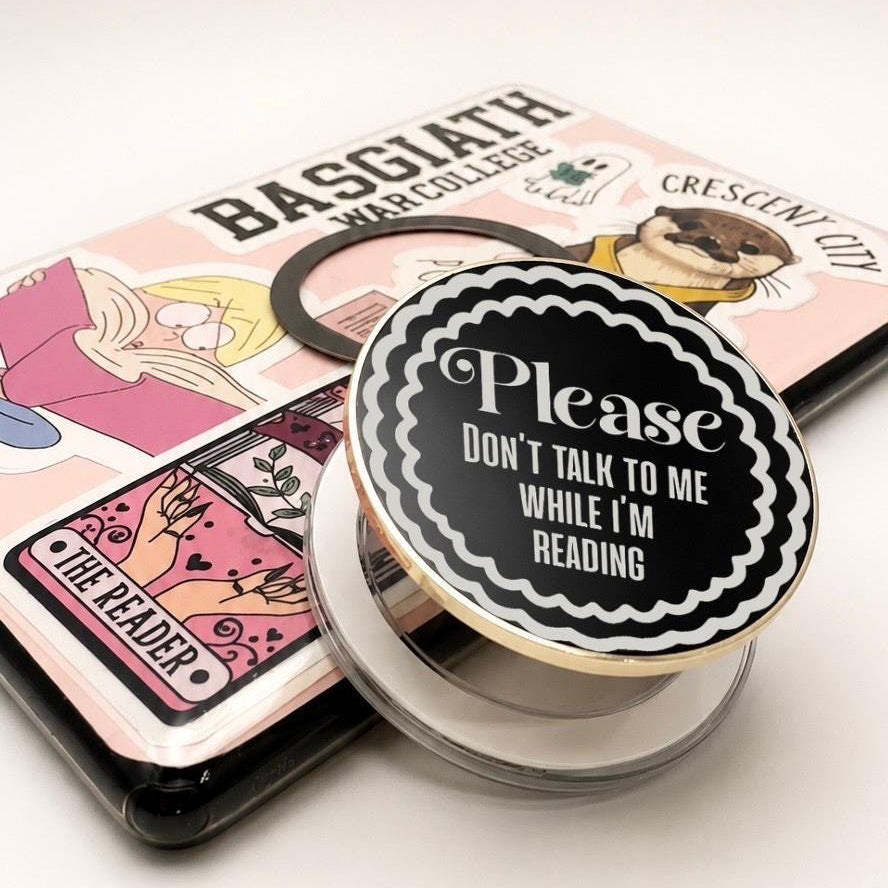     Close-up of Don’t Talk To Me While I’m Reading Metal Kindle MagSafe Grip with bold reading quote and scalloped border design.