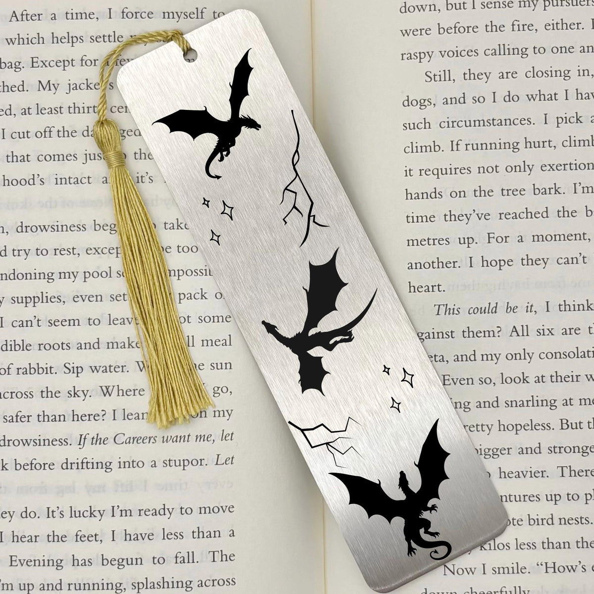 Brushed silver Fantasy Dragons Metal Bookmark with gold tassel on top of an open book