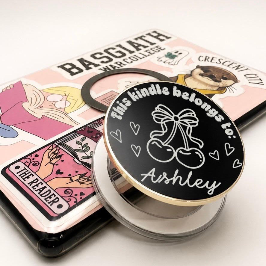     Close-up of Personalised Name Cherries Metal Kindle Grip with cherry and bow design, custom name Ashley and gold edging.