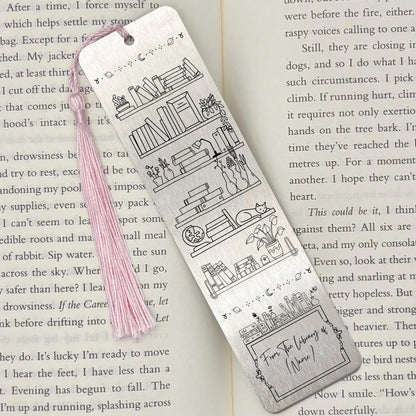 A brushed silver Personalised Name Library Shelf Metal Bookmark on and open book with a pink tassel