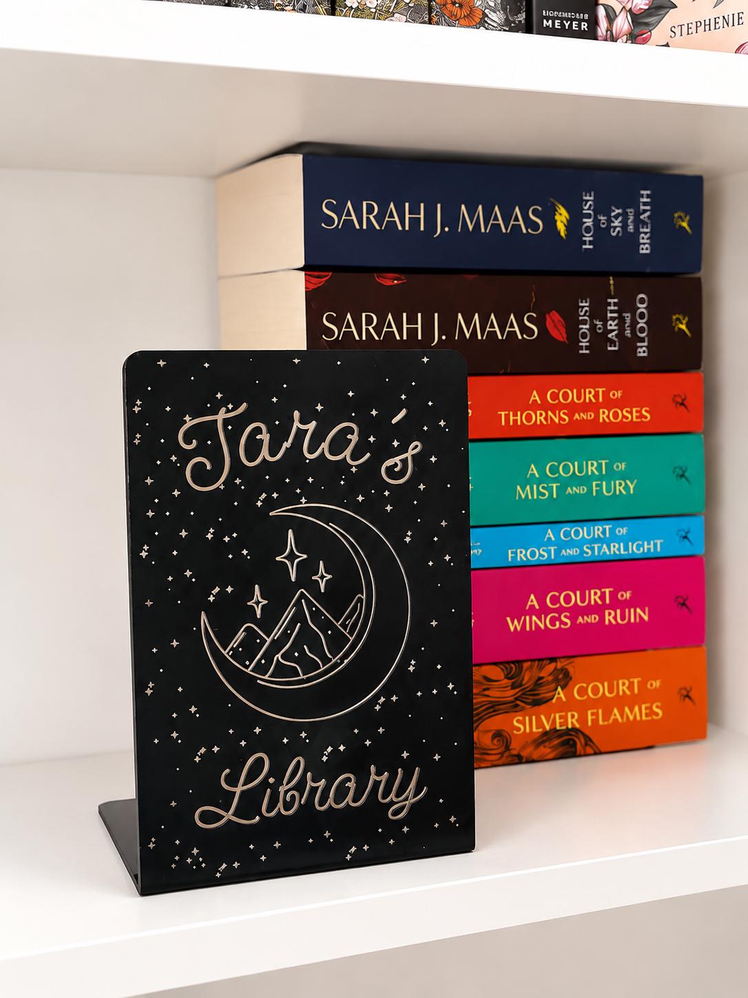     Personalised Name Library Metal Bookshelf Sign Bookends with celestial moon and mountain design displayed beside fantasy books